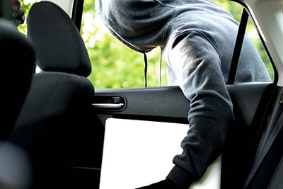 Thief stealing a laptop out of a open car window